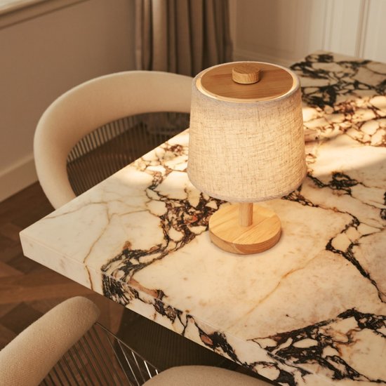Tafellamp met linnen kap, houten voet en bovenzijde, geplaatst op een marmeren tafel.