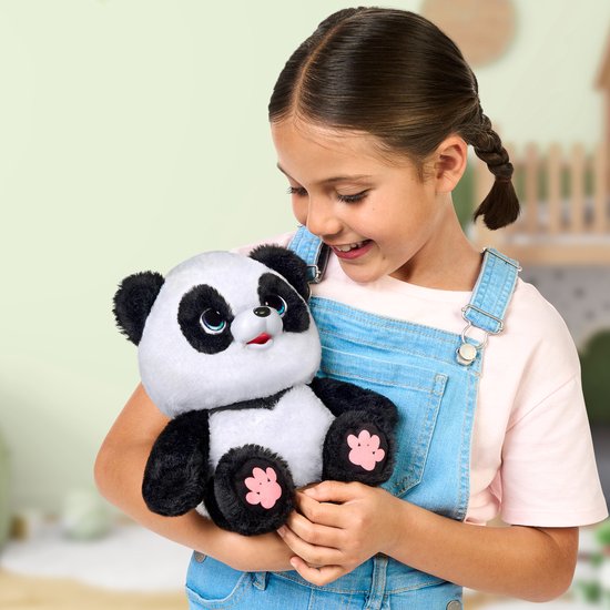 Meisje met gepofte vlechten in denim tuinbroek houdt panda knuffel vast.