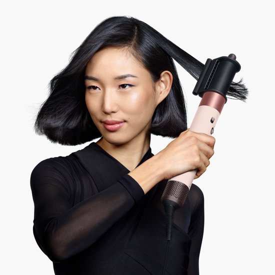 Vrouw met kort, donker haar gebruikt de Dyson Airwrap met een ronde borstel opzetstuk.