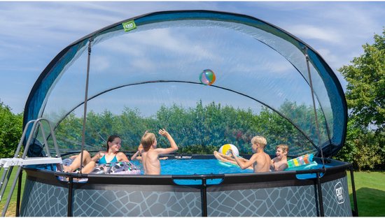 Vier kinderen spelen in een rond zwembad met een koepel en zwemmen met ballen en ringen.