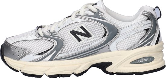 Zijzicht van witte New Balance 530 sneakers, zilveren accenten, zwarte 'N' en crèmekleurige zool.