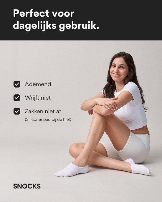 Vrouw met lang bruin haar, gekleed in een witte crop top en witte korte broek, zittend op de grond, met witte enkelsokken.