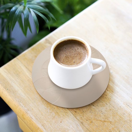 Un sous-verre rond beige à motif de cercles sur lequel repose une tasse de café.