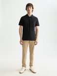 Man met zwart poloshirt en beige broek.