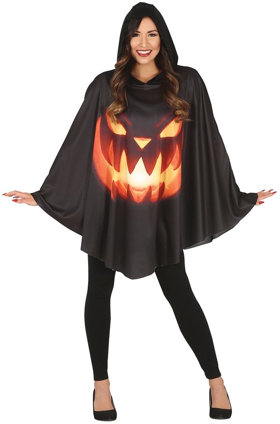 Vrouw in zwart pompoenponcho met capuchon en gloeiend gezicht, gedragen over een zwarte legging.