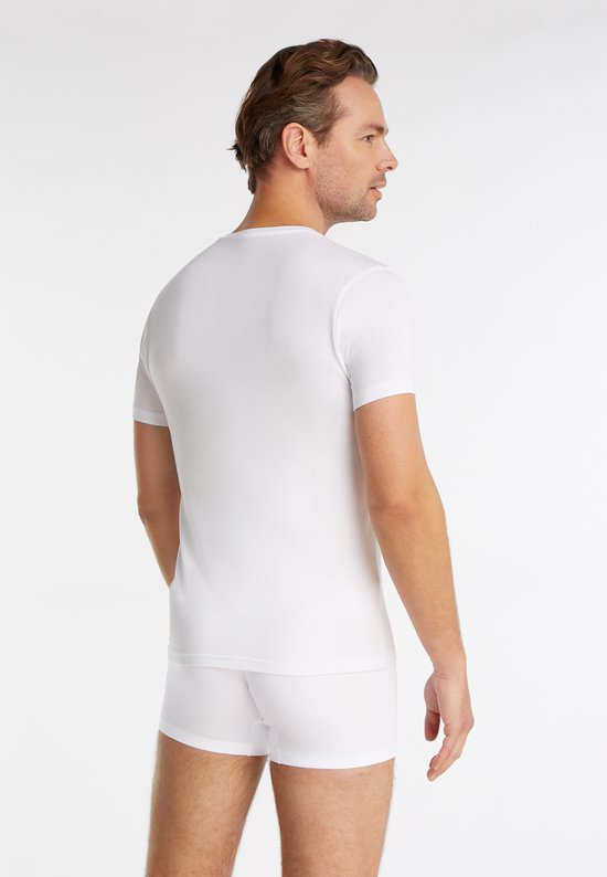 Man met donker haar, van achteren, in wit V-hals shirt en witte boxershort.