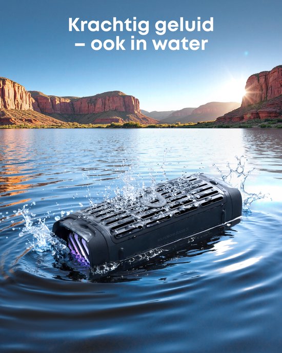 Zwarte Soundcore speaker in het water met splash-effect, tegen de achtergrond van een woestijnlandschap.
