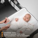 Baby op een grijze commode van een campingbedje. Gewicht- en leeftijdsindicatie.