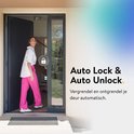 Vrouw in roze broek en wit shirt loopt een donkergrijze deur in met Nuki Smart Lock icoon en tekst 'Auto Lock & Auto Unlock'.