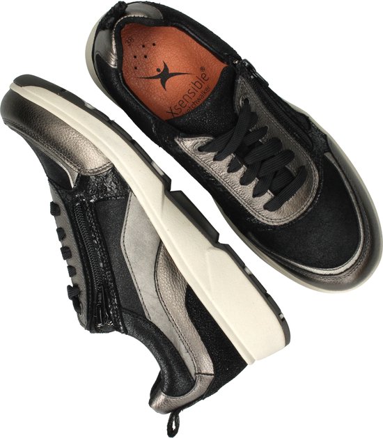 Zwarte en zilverkleurige sneakers met veters en ritssluiting, met binnenzool zichtbaar.