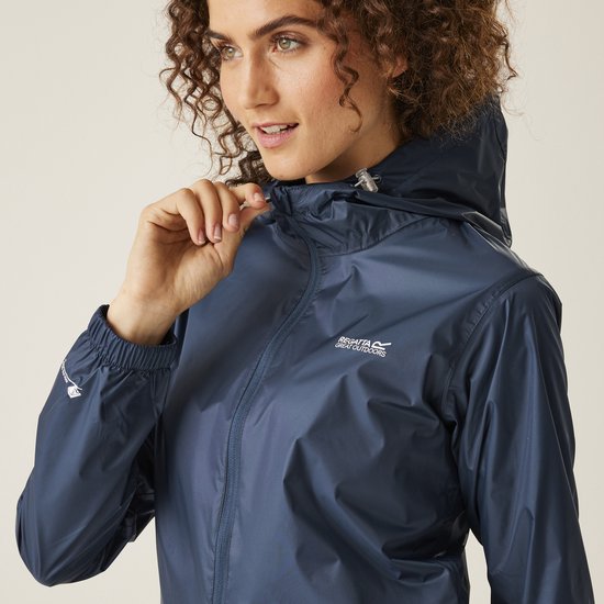 Close-up van een model dat de rits van een donkerblauwe regenjas sluit.