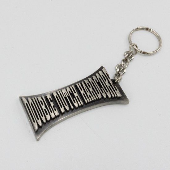 Zilverkleurige sleutelhanger met de tekst 'DOUBLE DUTCH HARDCORE' in reliëf.