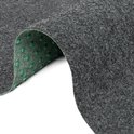 Tapis gris foncé avec un bord courbé et des picots verts en dessous.
