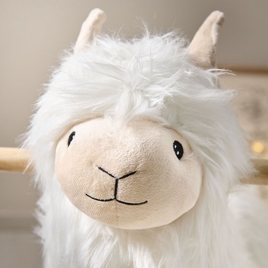 Close-up van het gezicht van een wit Alpaca hobbelpaard met pluizige vacht.