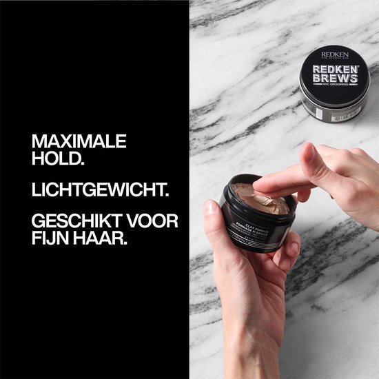 Hand met kleipomade potje, met tekst 'MAXIMALE HOLD. LICHTGEWICHT. GESCHIKT VOOR FIJN HAAR.'