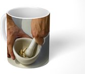 Mok - Iemand maalt bonen in een vijzel - 350 ML - Beker