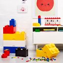 Een diverse collectie Lego opbergdozen in verschillende maten en kleuren (rood, geel, blauw, wit, zwart) en losse Lego-blokjes.