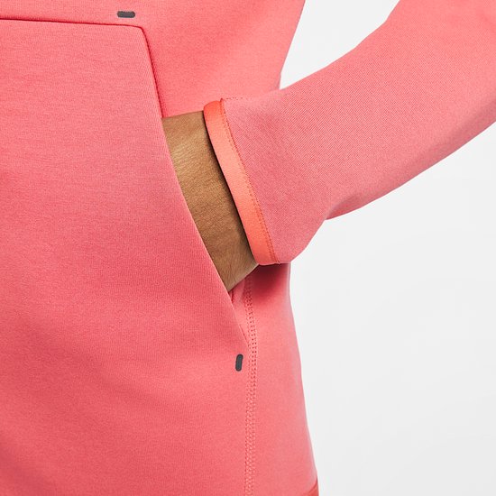 Detail van de zak van de koraalroze Nike Tech Fleece-hoodie met contrasterende rand.