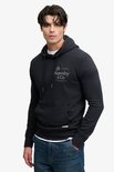 Model draagt donkerblauwe hoodie met witte onderlaag en spijkerbroek.