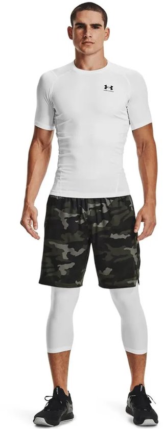 Man met wit Under Armour Heatgear shirt, camouflage shorts en witte driekwart legging.