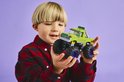 Jongen met groene LEGO monster truck met grote wielen en paarse velgen.