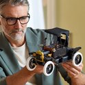 Man houdt een zwarte LEGO Ford Model T met witte banden vast. Zwarte kap, gouden koplampen.