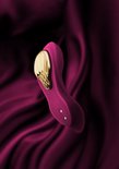 Vibrateur violet avec insert doré sur tissu violet ondulé.