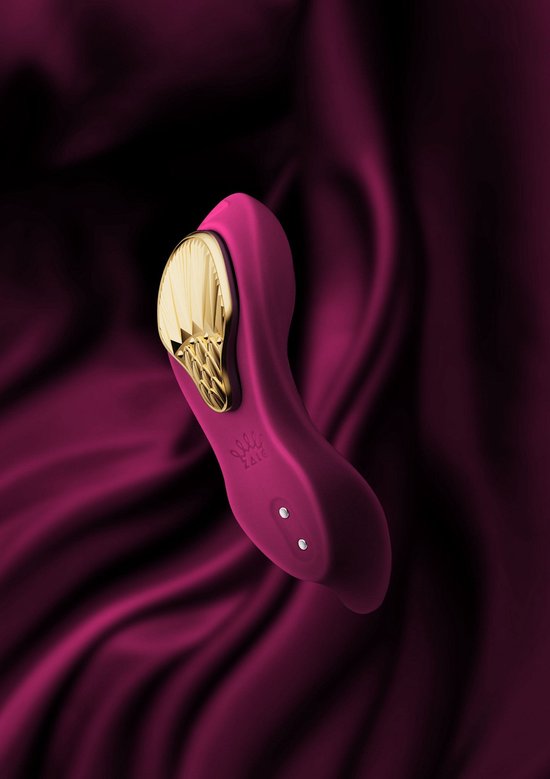 Vibrateur violet avec insert doré sur tissu violet ondulé.