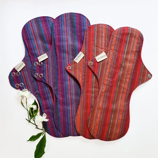 Vier herbruikbare Eco Femme maandverbanden, twee rood/oranje gestreept en twee paars/blauw gestreept, met drukknopen.