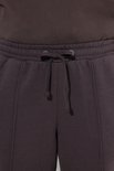 Gedetailleerde opname van de elastische tailleband met striksluiting van een donkerbruine joggingbroek.