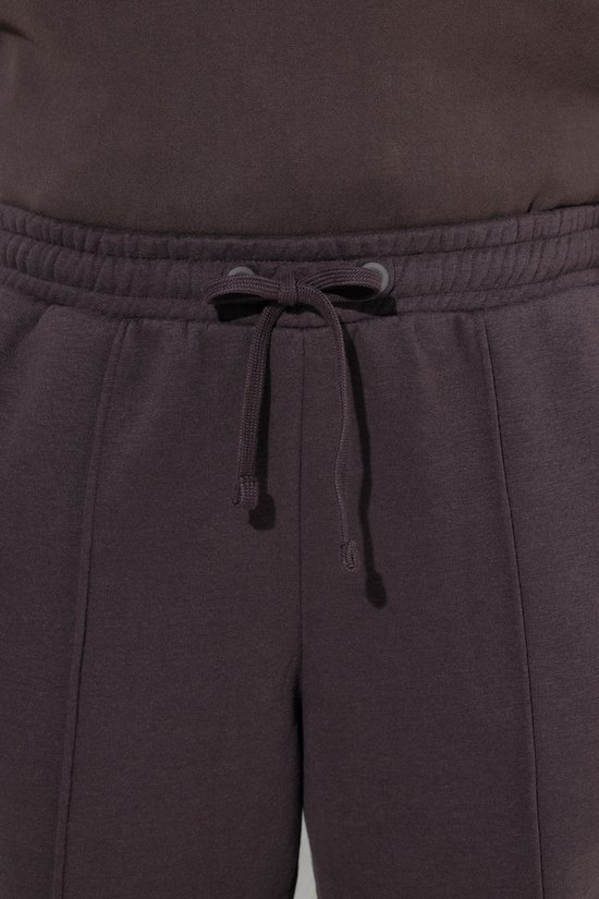 Gedetailleerde opname van de elastische tailleband met striksluiting van een donkerbruine joggingbroek.