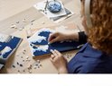 Une femme construit avec des briques LEGO une version 3D de La Grande Vague, avec des briques bleues et blanches pour les vagues.