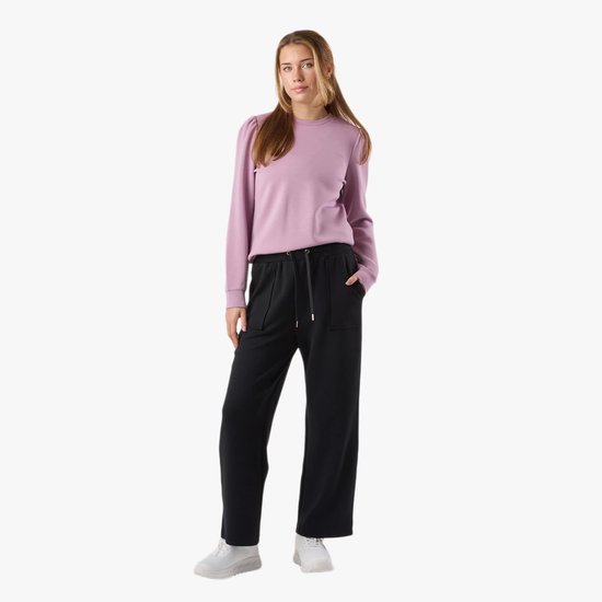 Model met lange blonde haren draagt een lichtpaarse trui met pofmouwen en een zwarte broek met hoge taille, koord en zakken.