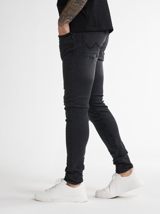 Zwarte Petrol Industries skinny jeans voor heren met achterzakken, gedragen met witte sneakers.