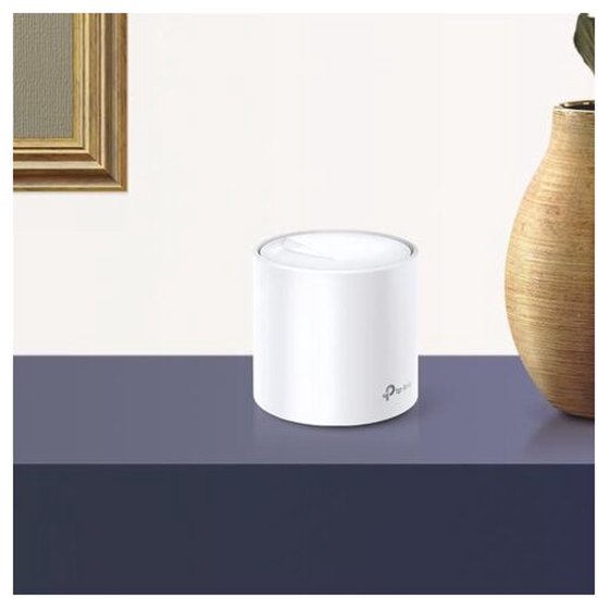 Een witte, cilindrische TP-Link Deco X20 mesh wifi unit op een donkerblauwe tafel, naast een vaas.