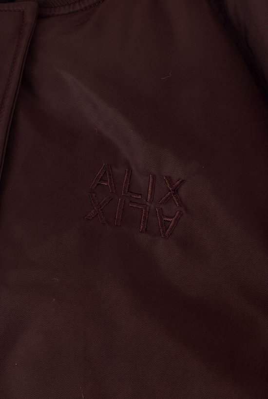 Detail van geborduurd ALIX logo op bruine bomberjack.