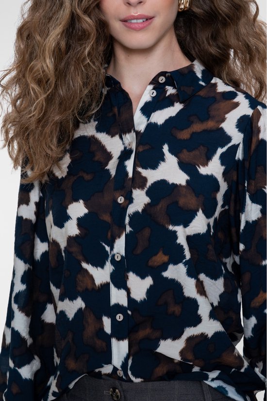 Close-up van de kraag en knoopsluiting van een blouse met abstracte print in blauw, bruin en crème.