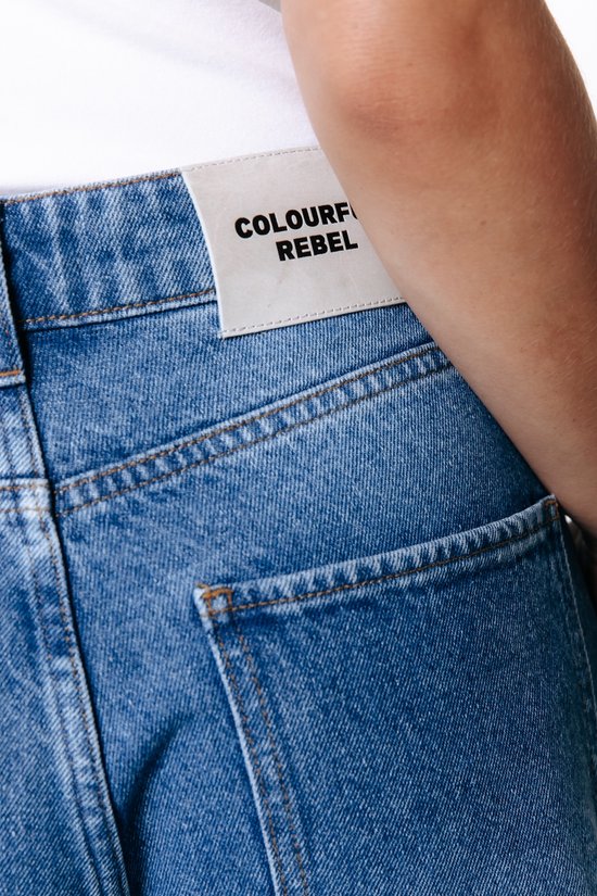 Close-up van de achterkant van een spijkerbroek met een label van 'Colourful Rebel'.