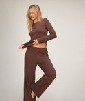 Bruine pyjamaset in geribbelde stof met een knoopsluiting en geschulpte randen, gedragen door een blond model.