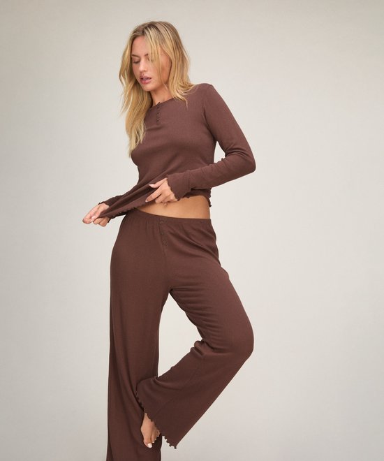 Bruine pyjamaset in geribbelde stof met een knoopsluiting en geschulpte randen, gedragen door een blond model.
