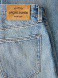 Bruin leren label met de tekst 'Crafted Jack & Jones With Care' op een blauwe jeans.