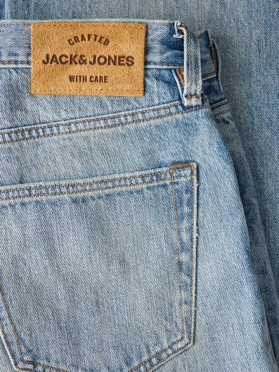 Bruin leren label met de tekst 'Crafted Jack & Jones With Care' op een blauwe jeans.