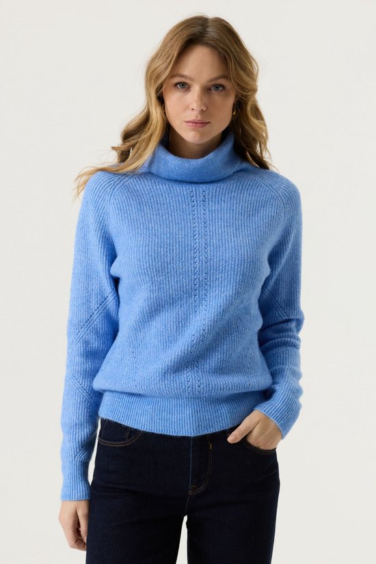 Model draagt een lichtblauwe Garcia coltrui met geribbelde details, gecombineerd met een donkere jeans.