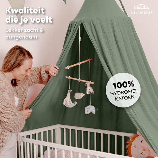 Vrouw bij groen hydrofiel katoenen hemeltje boven wieg met baby-mobiel, Lilimaus.