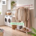 Roze kledingrek met beige kleding in een wasruimte naast twee wasmachines. Tekst: 'Ook geschikt voor natte was'.