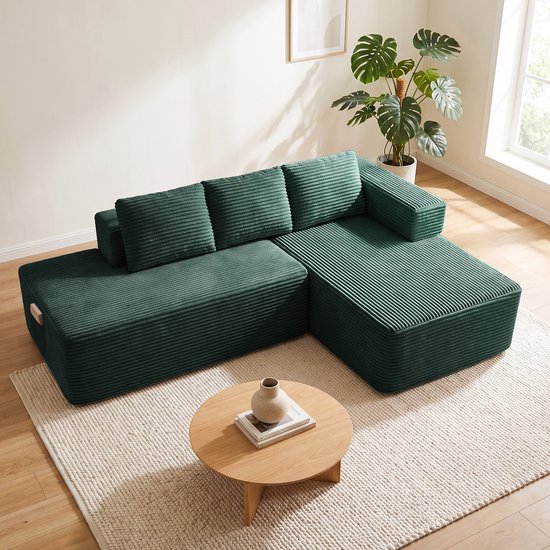 Luchtfoto van een modulaire donkergroene corduroy bank, opgesteld in een woonkamer met een salontafel.