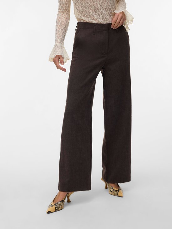 Model van voren gezien, draagt een donkerbruine broek met wijde pijpen en een pinstreep. Draagt ook een beige kanten blouse.