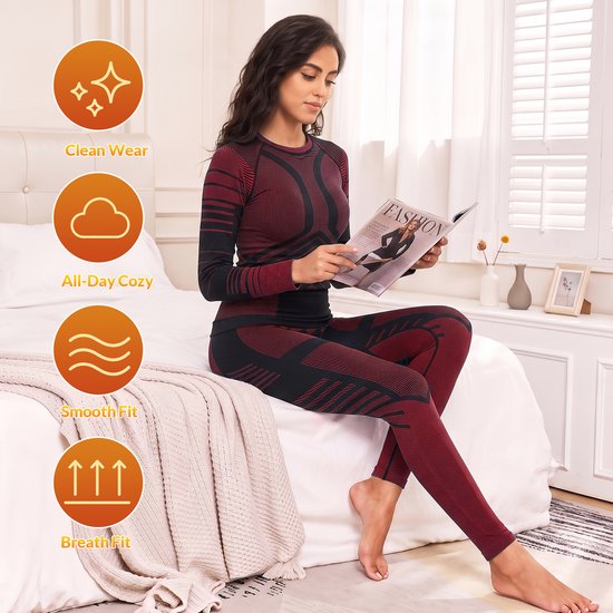 Vrouw in rood en zwart thermisch ondergoed, zittend op een bed, met iconen voor 'Clean Wear', 'All-Day Cozy', 'Smooth Fit' en 'Breath Fit'.