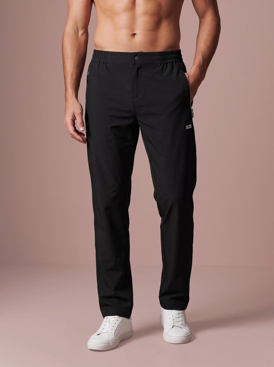 Model draagt een zwarte sportbroek in stretchstof met twee zakken met rits, het Sjeng Sports logo op de linkerheup.