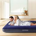 Koppel ontspant op een donkerblauw Intex luchtbed in een modern interieur.